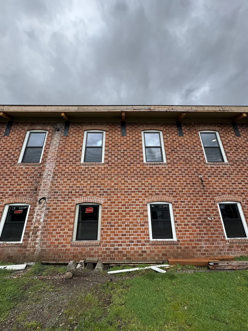 Eight new black-frame windows installed in a two-story brick building