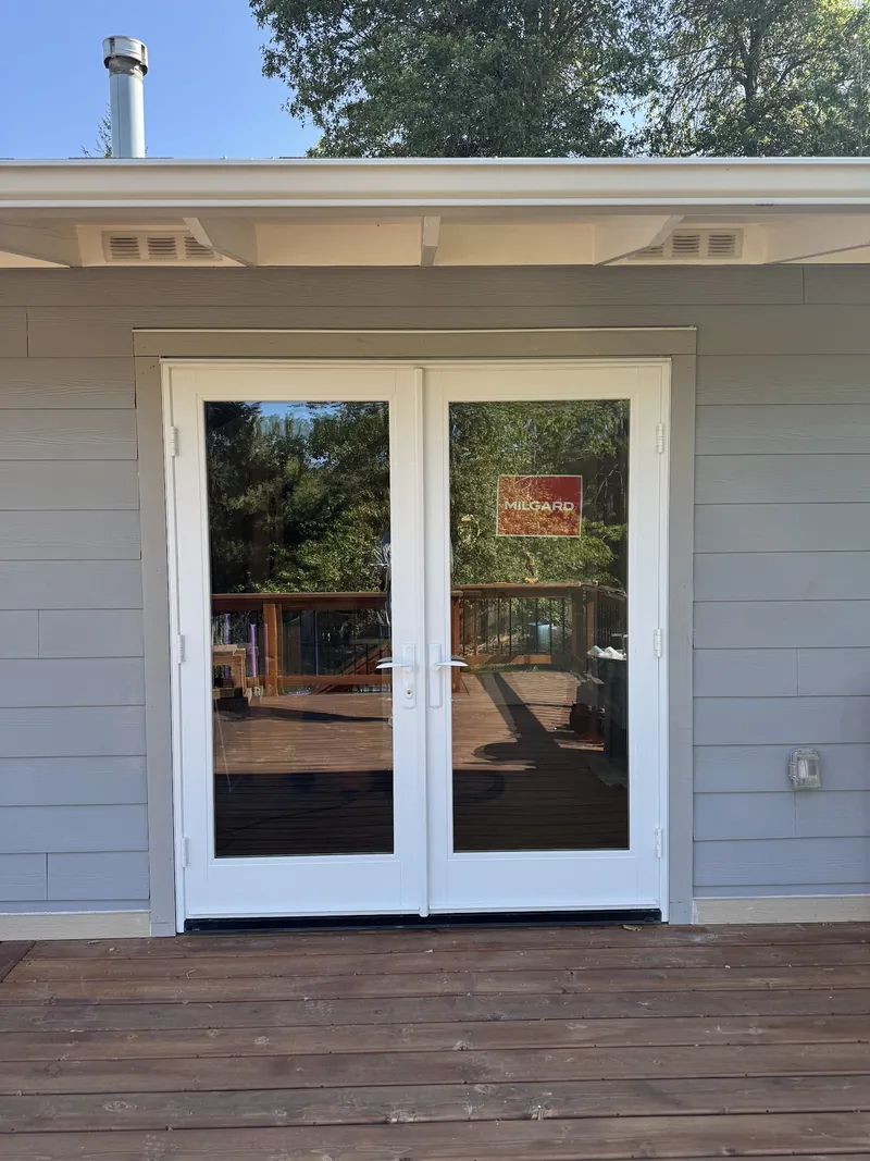 New white Milgard French patio doors installed off a wood deck