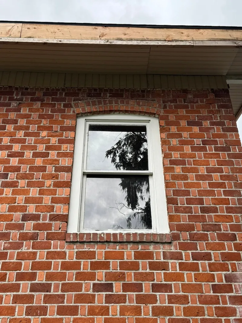 New white double-hung window set into an arched brick opening